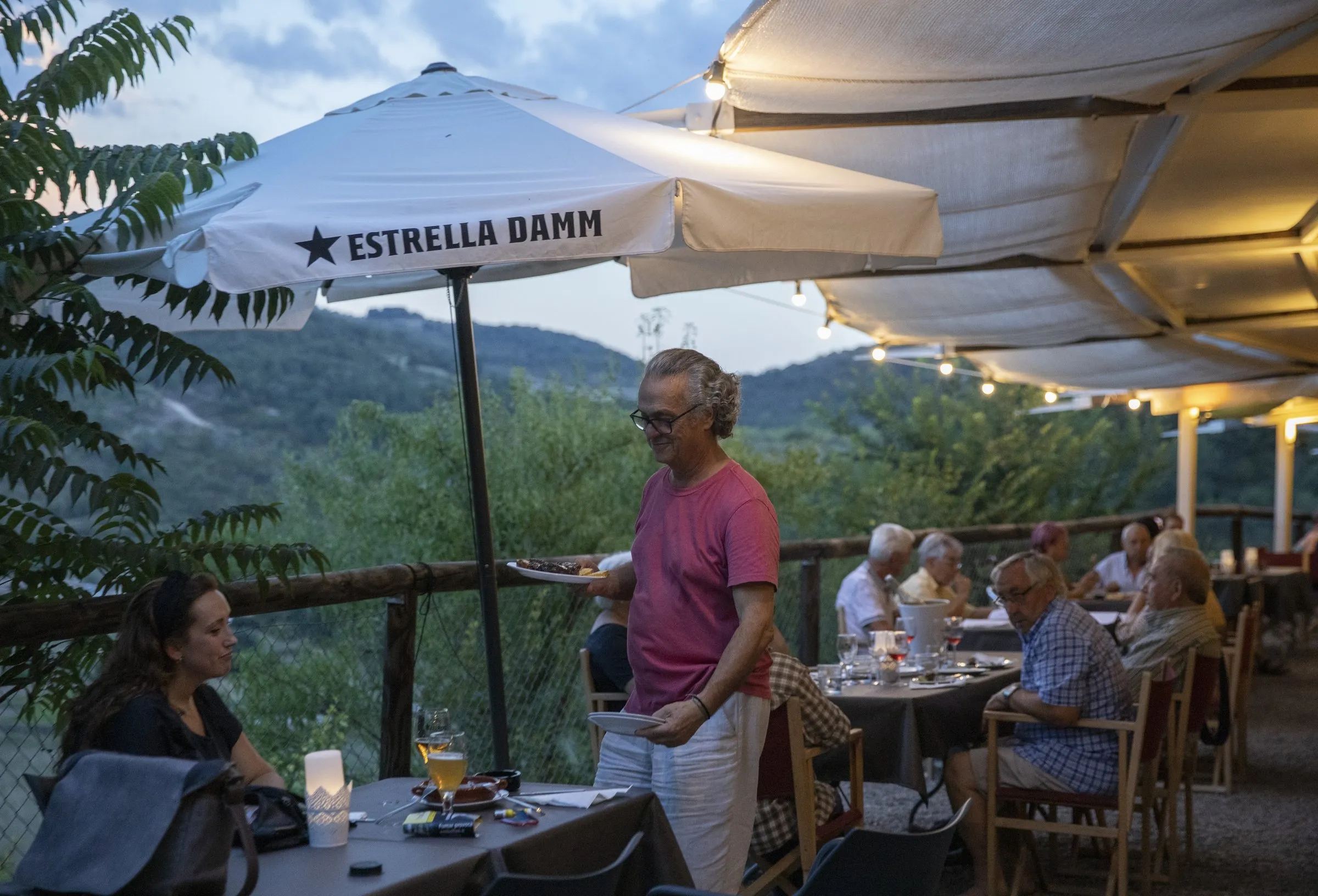 Claudio sirve platos en la terraza llena, con el valle al fondo